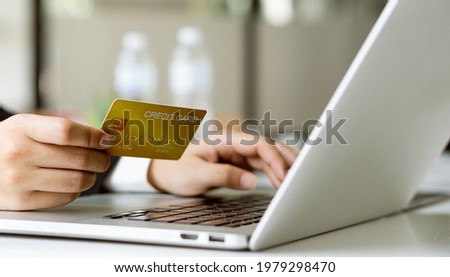 Young women hold credit cards and use laptop computers and to shop online, e-commerce, internet banking, spend money, work from home.