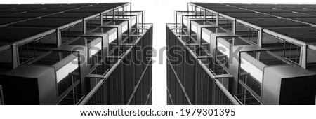 Low angle close-up fragment of industrial building with lift shaft and perforated panels. Modern industry and minimal architecture background with modular structure of glass and metal framework.  Royalty-Free Stock Photo #1979301395