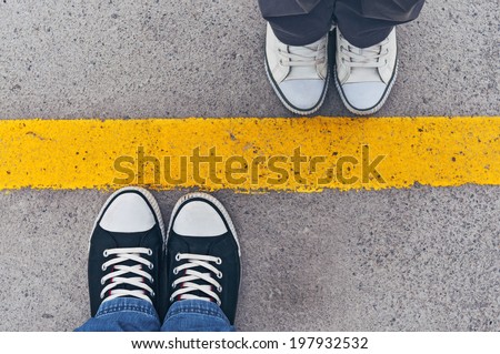Top view of sneakers from above, male and female feet in casual footwear standing at dividing frontier line. Royalty-Free Stock Photo #197932532