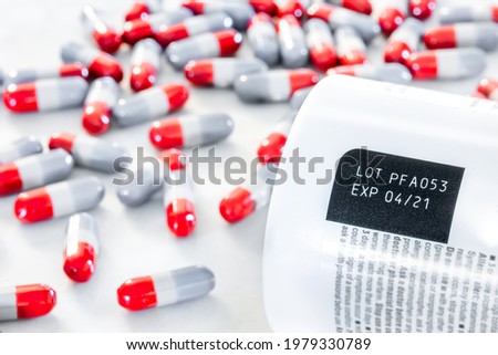 Expired date and lot number label printed on medicine bottle with blurred background of pile of painkiller pills awareness expiration information on packaging from the manufacturer. Medication. Royalty-Free Stock Photo #1979330789
