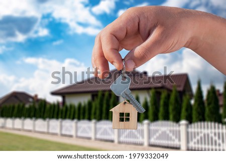 Man holds the keys to the house in his hands against the backdrop of residential buildings. Concept for buying and renting apartments