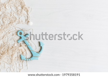 Sea background with fishing net, anchor and seashells top view on white wooden background. Summer sea holiday background. 