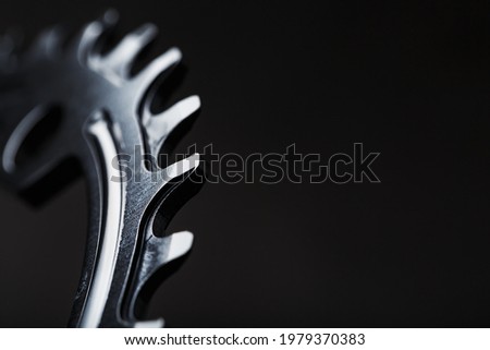 Black Star of the Narrow Wide Bicycle Connecting Rod System. A pattern of teeth of a running bicycle star on a black background. Dark key macro Royalty-Free Stock Photo #1979370383