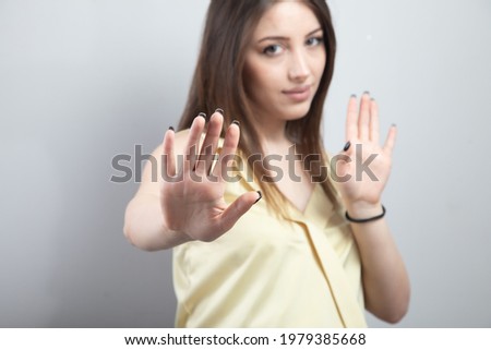 Young serious beautiful woman showing stop sign