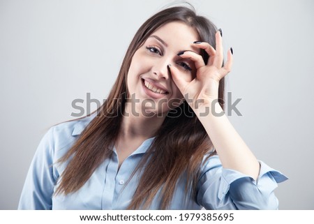 young woman showing okay sign over eyes