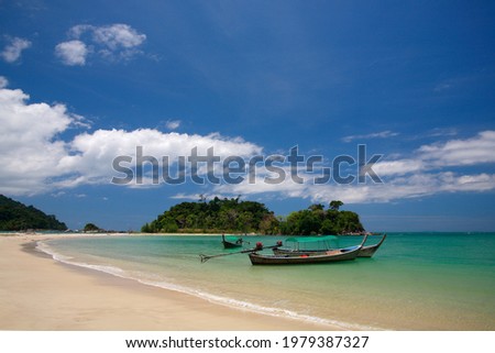 Scenery of green trees on the small islands with long tail boats on turquoise sea and white sand. The picture is taken on the strong daylight day with blue sky and white clouds from south of Thailand.