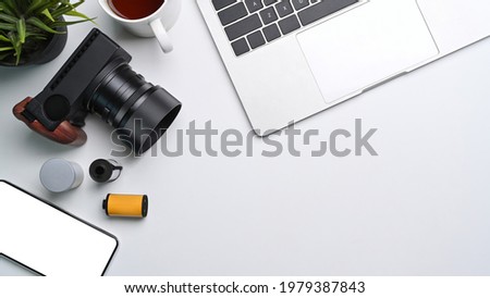 Above view of laptop computer, coffee cup and camera accessories on photographer workspace.