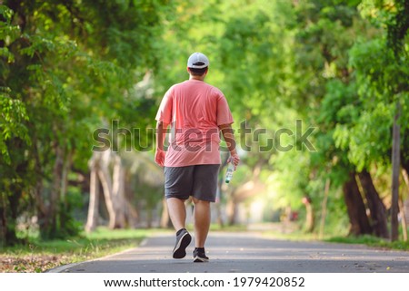 Fat man exercising By walking to burn fat And run slowly to exercise in the park Royalty-Free Stock Photo #1979420852
