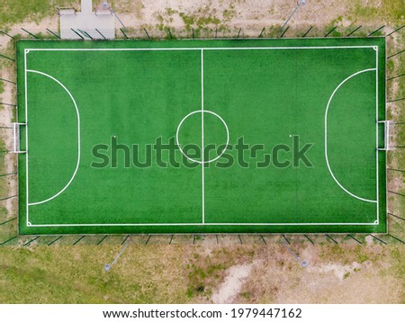 Outdoor fenced illuminated mini football field in spring day, vertical aerial view close-up 
