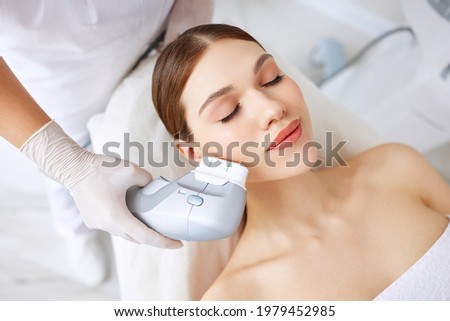 From above of relaxed young female client getting SMAS ultrasound face lifting massage with professional equipment in beauty center Royalty-Free Stock Photo #1979452985