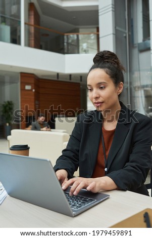 Young businesswoman sitting at the table and typing on laptop computer at office