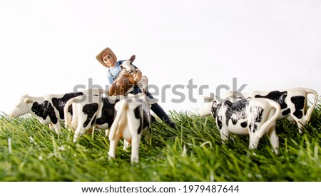 Miniature toy figures Farmer with calf and cows in a field Royalty-Free Stock Photo #1979487644