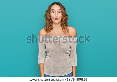 Beautiful young caucasian woman wearing casual clothes making fish face with lips, crazy and comical gesture. funny expression. 