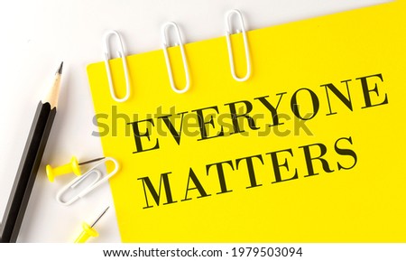 EVERYONE MATTERS word on the yellow paper with office tools on the white background