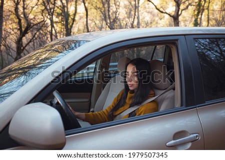 A beautiful young happy woman driving her car in the woods. the idea and concept of travel and discovery, Fall Getaway