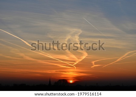 contrails in the sky at sunset due to engine exhaust produced by airplanes Royalty-Free Stock Photo #1979516114