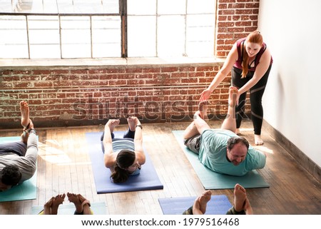 Trainer assisting her student doing a Balasana pose