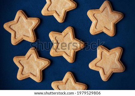 Top view of delicious gingerbread cakes in the shape of stars lying on a blue background, depicting the night starry sky. Holiday.