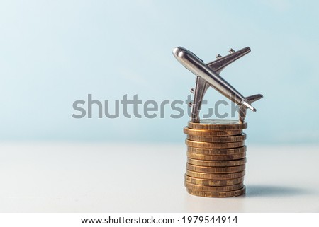The airplane stands on a stack of coins. A toy little airplane is lying sideways on the gold coins. Royalty-Free Stock Photo #1979544914