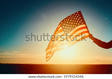 Waving american flag outdoors. Hand holds usa national flag at sunset. 4th July Independence Day