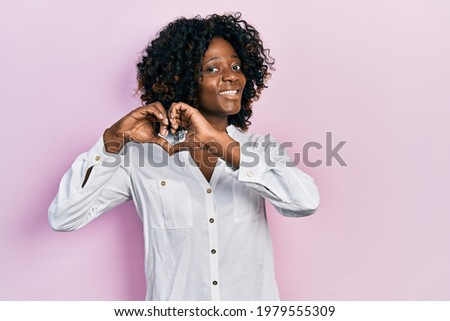 Young african american woman wearing casual clothes smiling in love doing heart symbol shape with hands. romantic concept. 