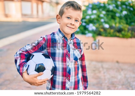 Adorable caucasian boy smiling happy holding soccer ball standing at the park.