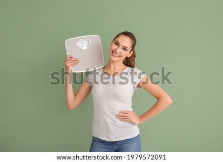 Young woman with weight scales on color background Royalty-Free Stock Photo #1979572091