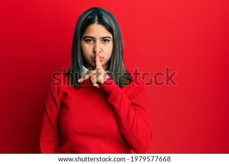 Young latin woman wearing casual clothes asking to be quiet with finger on lips. silence and secret concept. 