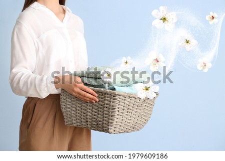 Young woman with clean laundry on color background