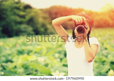 young woman photographer taking photo of blooming lotus at park