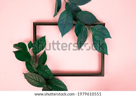 photo frame and green leaves on a pink pastel background. Artwork mockup with copy space