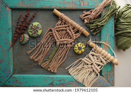 Beige and ecru colored mini macrame and macrame ropes on a blue background. 
Colored stone paintings
