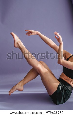 Female dancer sitting on floor with raised legs and arms during dance