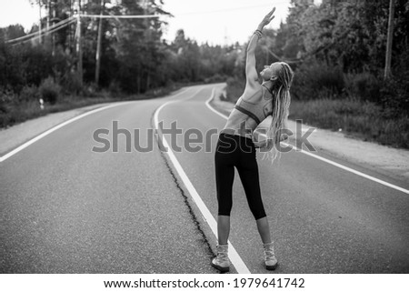 Woman warm-up before jogging on the road. Black and white photo.