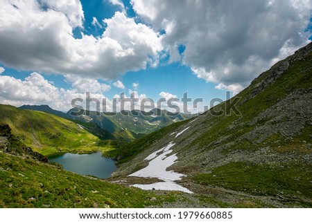 mountain summer landscape with alpine lake. beautiful nature scenery of fagaras mountain ridge, romania. sunny weather with fluffy clouds on the sky. popular travel destination