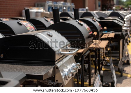 A collection of preassembled grills and smokers for sale are seen outside a retail store. 