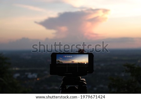 Smartphone recording video time lapse on tripod with beautiful sky in twilight time.