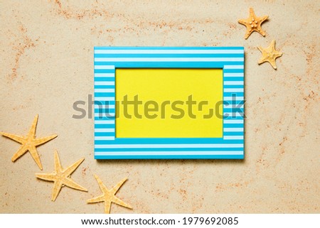 Picture frame with copy space and starfish on sand as a summer background