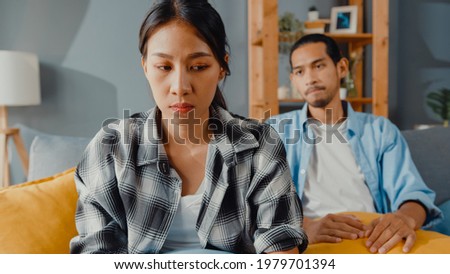 Upset asian couple wife sit on couch listen to furious husband yelling feel unhappy talk negative to her. Couple have fight or disagreement at home, Couple problem, family married toxic relationship. Royalty-Free Stock Photo #1979701394