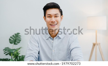 Portrait of successful handsome executive businessman smart casual wear looking at camera and smiling, happy in modern office workplace. Young Asia guy talk to colleague in video call meeting at home. Royalty-Free Stock Photo #1979702273