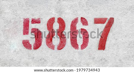 Red Number 5867 on the white wall. Spray paint.