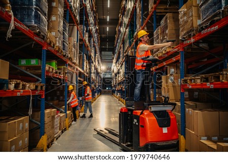Warehouse worker reading bar codes on products while standing forklift Royalty-Free Stock Photo #1979740646