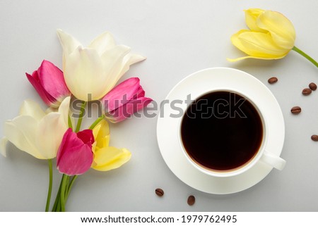 Cup of coffee with tulips on grey background with copy space. Top view