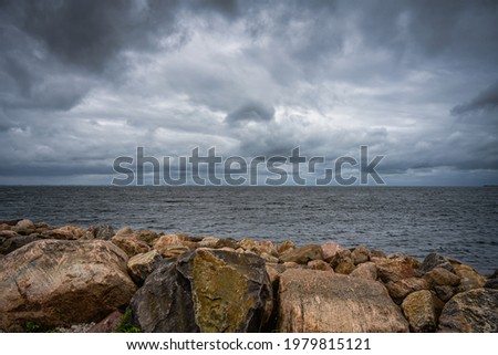 A beautiful, dramatic sky over the ocean. Stones in a wave breaker in the foreground. Picture from Malmo, Sweden