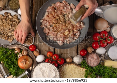 The chef prepares pizza with minced meat and mushrooms. In the photo, the cooking process. The chef adds spices to the filling. A very beautiful still life. In the foreground are the ingredients.
