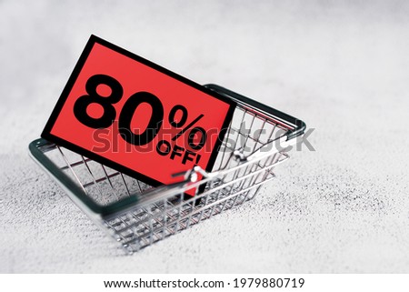 Red card mini grocery shopping basket with eighty percent discount sign, close up. Conceptual image of a clearance sale, seasonal discounts in shopping stores, black friday	