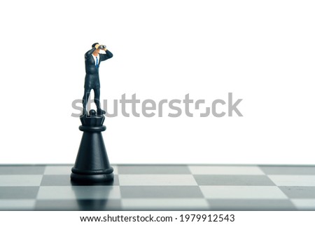 Businessman using binoculars standing above fortress castle chess pawn. Miniature tiny people toys photography. isolated on white background