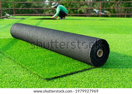 Roll of astroturf  or field turf matting of artificial grass soccer field,green lawn background with workers pave the  counterfeit grass. Royalty-Free Stock Photo #1979927969