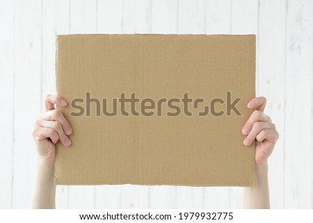 Human's hands holding up cardboard with copy space Royalty-Free Stock Photo #1979932775