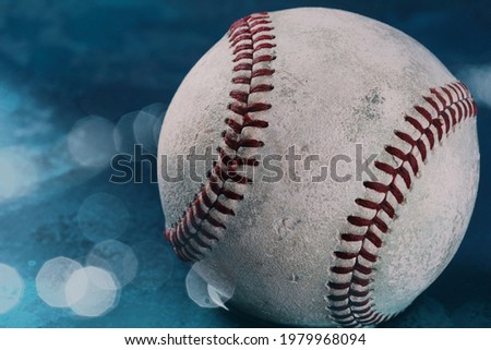 Used baseball ball on blurred blue bokeh background with copy space.
